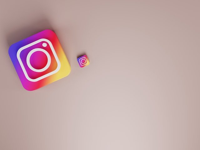 Two Instagram logos on a beige surface in the upper left corner of a photo as a featured image for a post about the best posting time on Instagram